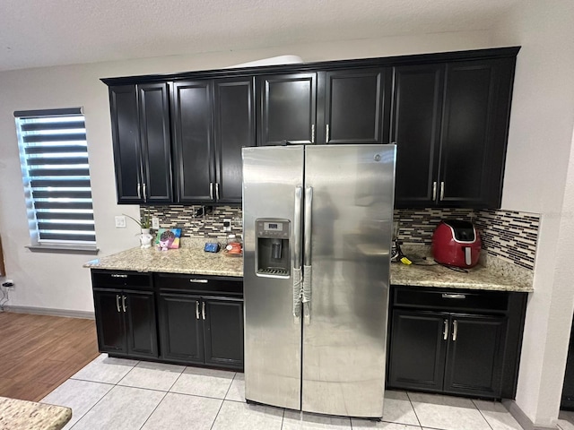 kitchen with backsplash, stainless steel refrigerator with ice dispenser, and dark cabinetry