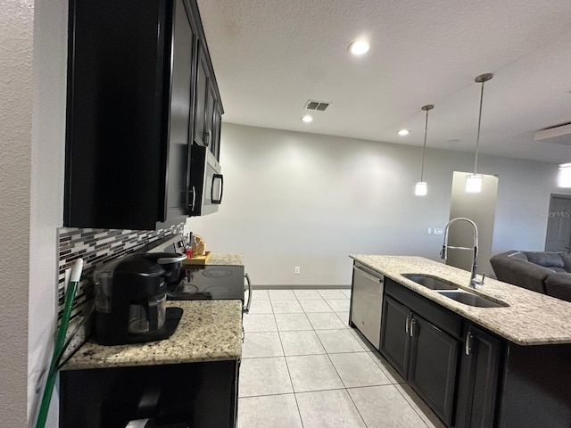 kitchen featuring visible vents, decorative backsplash, appliances with stainless steel finishes, dark cabinetry, and a sink