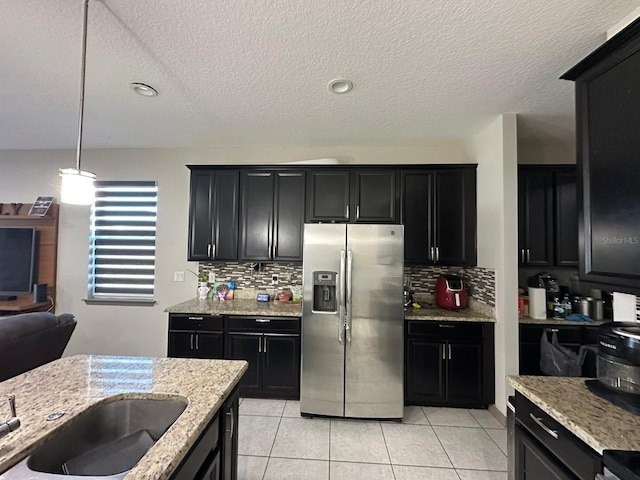 kitchen with light tile patterned floors, appliances with stainless steel finishes, light stone counters, and dark cabinets