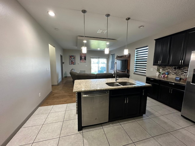 kitchen featuring dark cabinetry, appliances with stainless steel finishes, a sink, and light tile patterned flooring