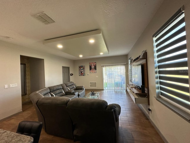 living area featuring baseboards, a textured ceiling, visible vents, and recessed lighting