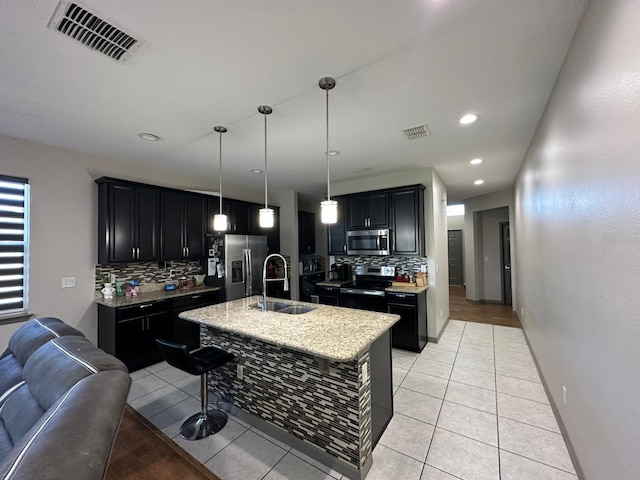 kitchen with appliances with stainless steel finishes, visible vents, a sink, and dark cabinets