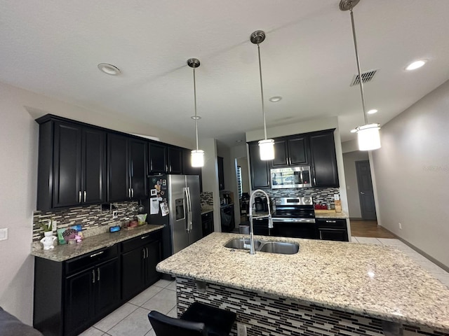 kitchen with light stone counters, dark cabinets, a sink, visible vents, and appliances with stainless steel finishes