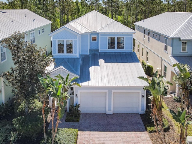 view of front of home with a garage, metal roof, decorative driveway, and a standing seam roof