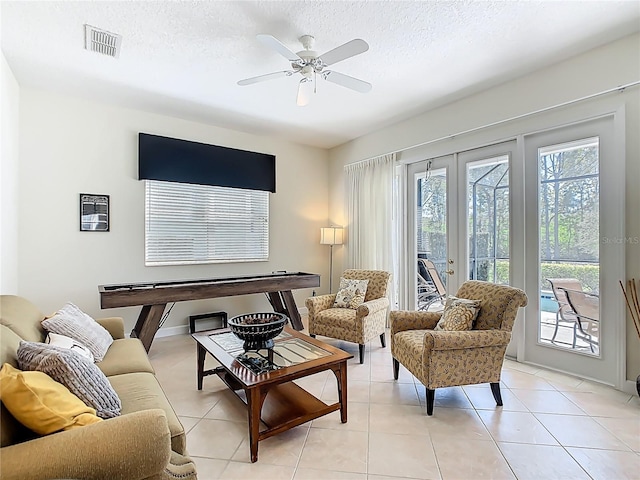 living area with french doors, visible vents, a textured ceiling, and light tile patterned floors