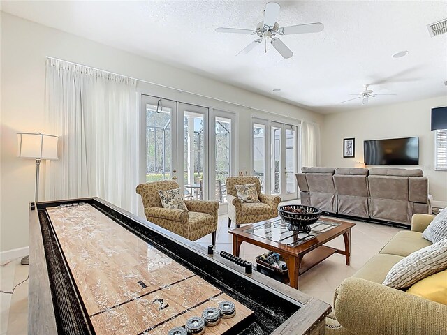 living area with a textured ceiling, visible vents, a ceiling fan, baseboards, and french doors