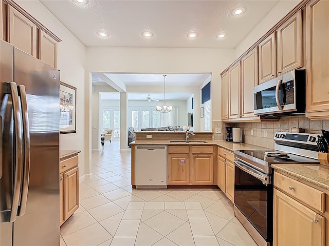 kitchen with light tile patterned floors, backsplash, a peninsula, stainless steel appliances, and a sink