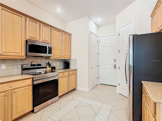 kitchen featuring light stone counters, light tile patterned floors, tasteful backsplash, light brown cabinetry, and appliances with stainless steel finishes