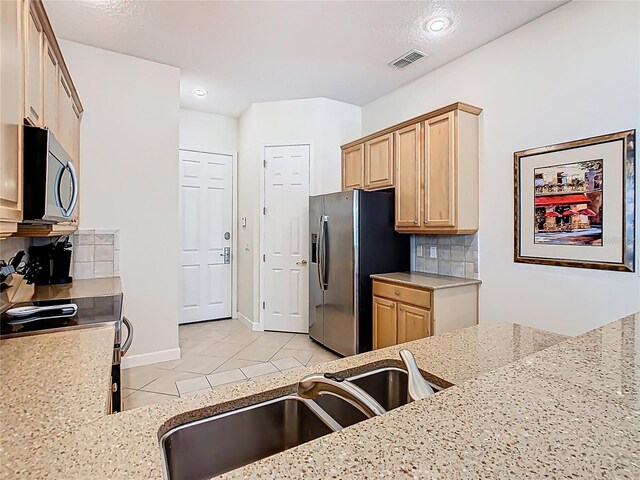 kitchen with light tile patterned flooring, stainless steel appliances, a sink, visible vents, and backsplash