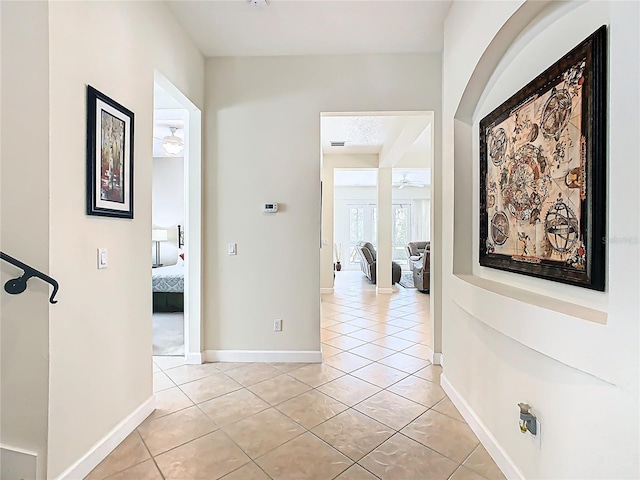 hallway featuring baseboards and light tile patterned flooring