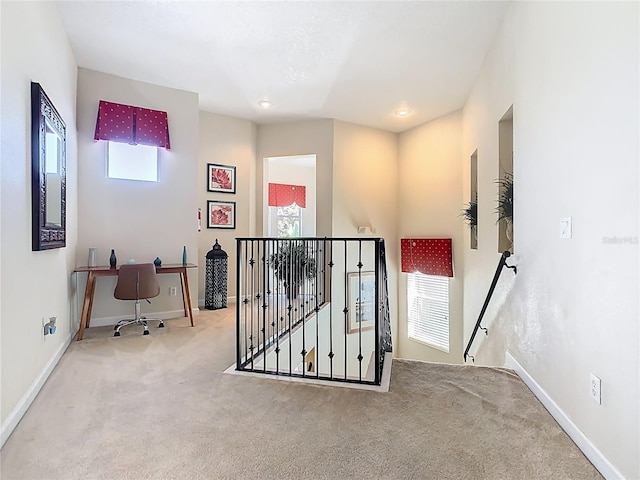 hallway featuring carpet floors, baseboards, and an upstairs landing