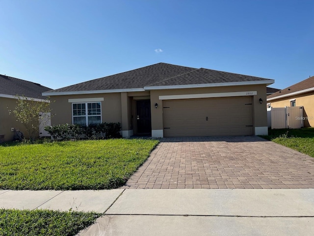 single story home featuring decorative driveway, stucco siding, an attached garage, a front yard, and fence