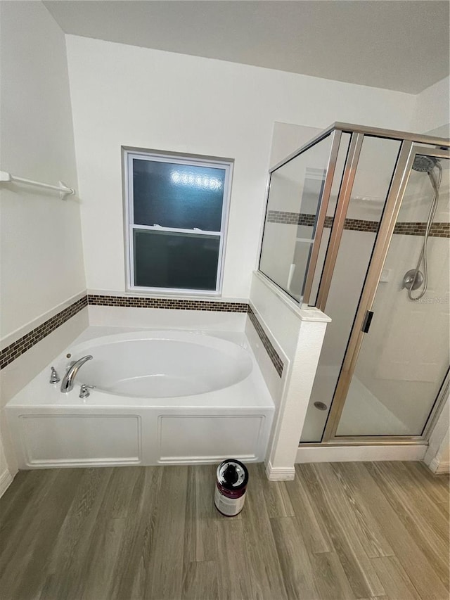 full bathroom featuring a garden tub, wood finished floors, and a stall shower