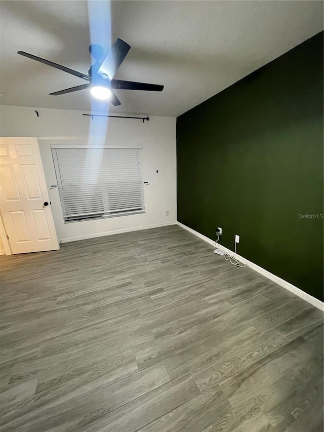 unfurnished room with a ceiling fan, baseboards, and wood finished floors