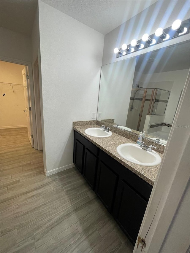 full bath with a sink, a shower stall, and wood finished floors