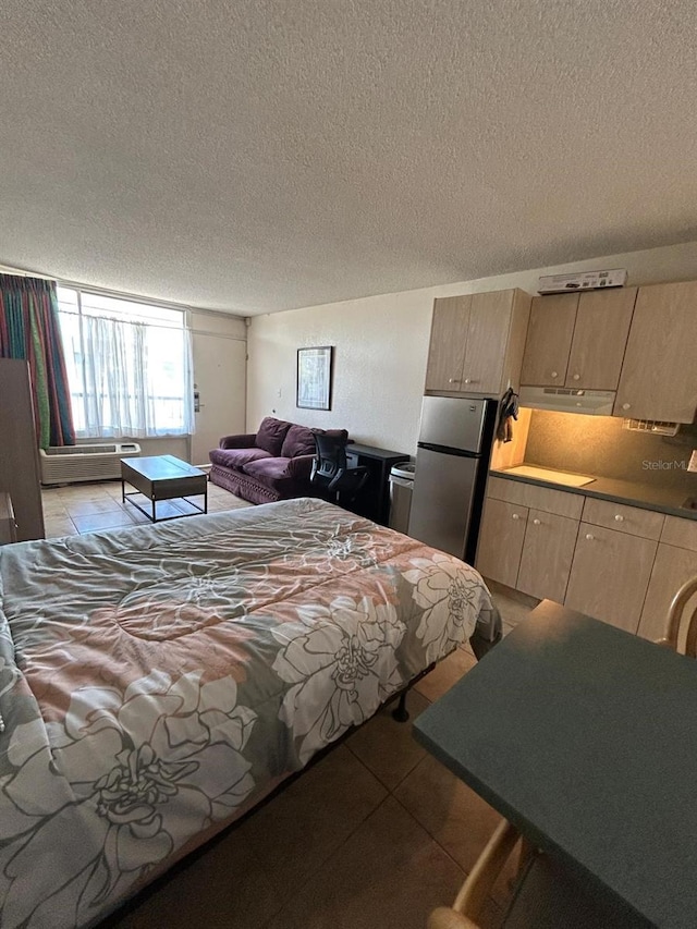 bedroom featuring a textured ceiling, light tile patterned flooring, and freestanding refrigerator