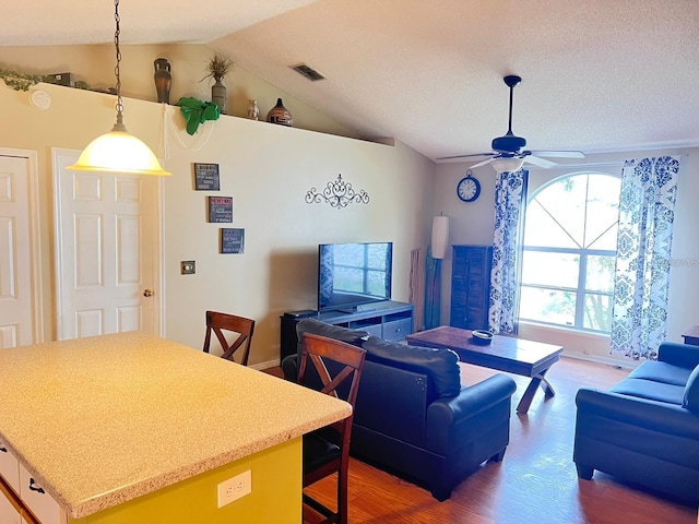 living room with light wood finished floors, visible vents, a ceiling fan, and vaulted ceiling