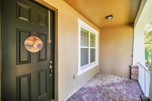 view of exterior entry with stucco siding and covered porch