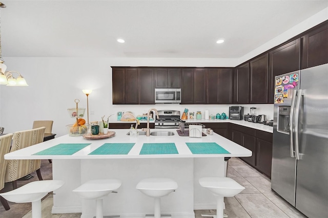 kitchen with a sink, appliances with stainless steel finishes, a breakfast bar area, light countertops, and light tile patterned floors