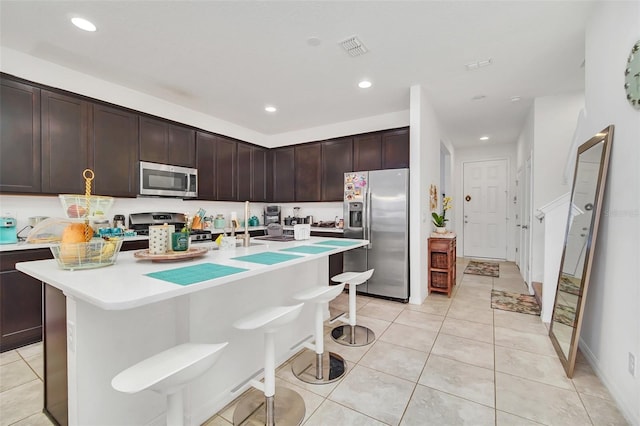 kitchen with a breakfast bar, light countertops, light tile patterned floors, and appliances with stainless steel finishes