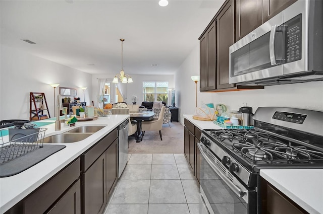 kitchen featuring visible vents, a sink, open floor plan, stainless steel appliances, and dark brown cabinetry