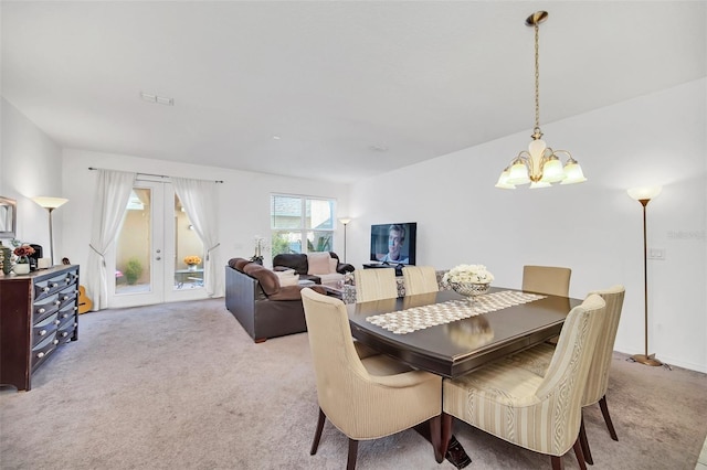 dining space featuring french doors, light colored carpet, and a notable chandelier