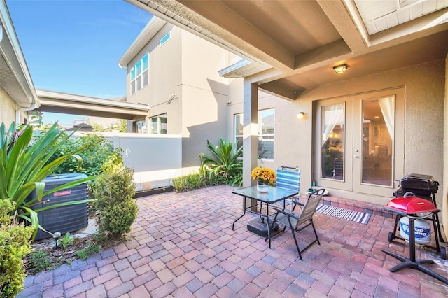 view of patio with cooling unit, french doors, and fence