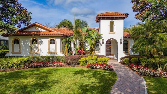 mediterranean / spanish-style house with a tile roof, a front lawn, and stucco siding