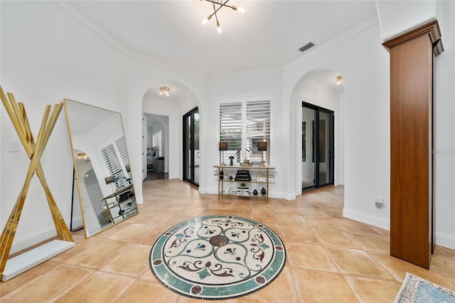 foyer with arched walkways, light tile patterned floors, visible vents, ornamental molding, and baseboards