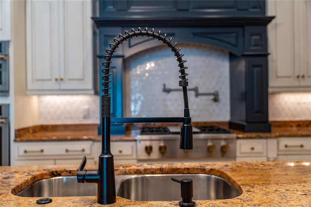 kitchen featuring light stone counters, white cabinets, and oven