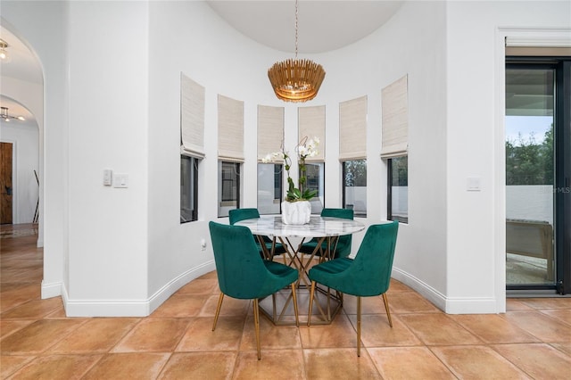 dining area featuring arched walkways, light tile patterned flooring, baseboards, and an inviting chandelier