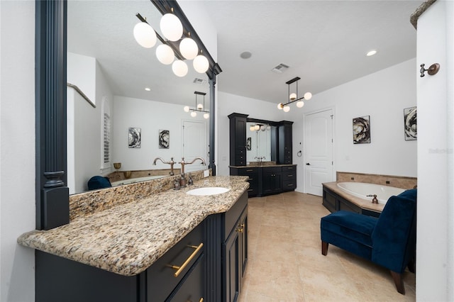 bathroom with a garden tub, visible vents, two vanities, and a sink