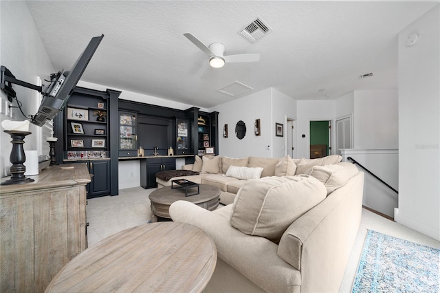 living room with attic access, light colored carpet, visible vents, and a textured ceiling