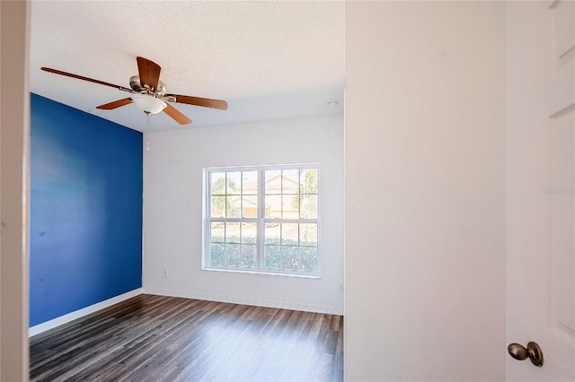 unfurnished room with dark wood-style floors, ceiling fan, baseboards, and a textured ceiling