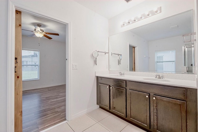 bathroom featuring baseboards, double vanity, a sink, and tile patterned floors