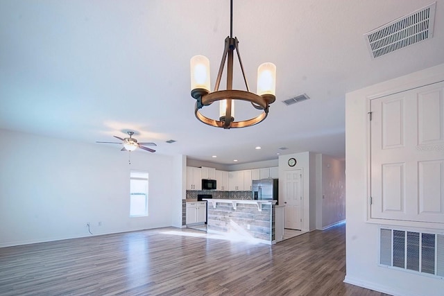 kitchen featuring stainless steel fridge, black microwave, and visible vents