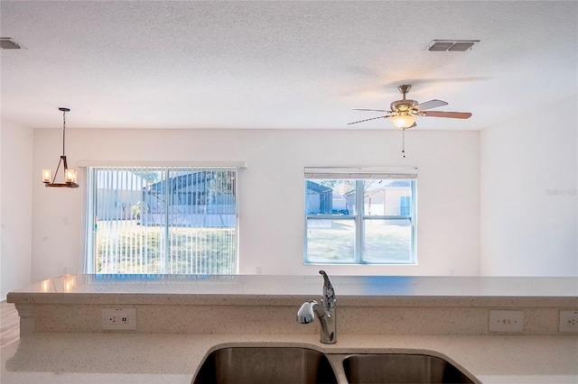 kitchen with plenty of natural light, a sink, visible vents, and light stone countertops