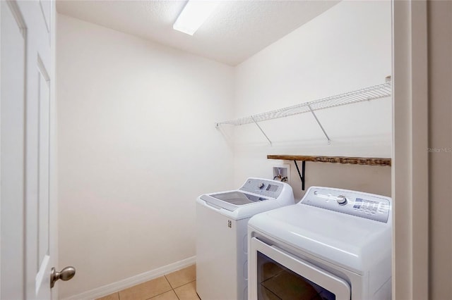 laundry area featuring light tile patterned floors, a textured ceiling, laundry area, baseboards, and washer and dryer