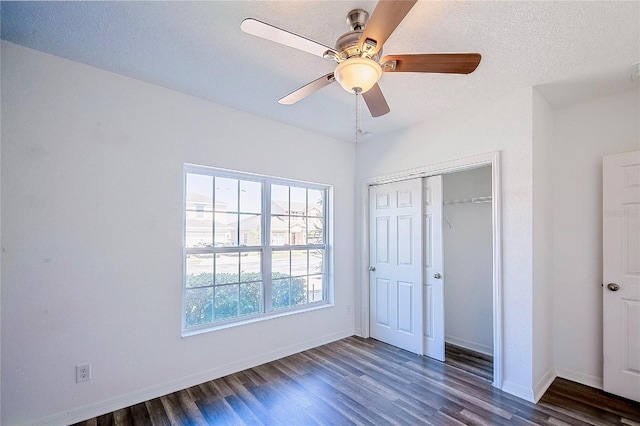 unfurnished bedroom with a closet, a textured ceiling, baseboards, and wood finished floors