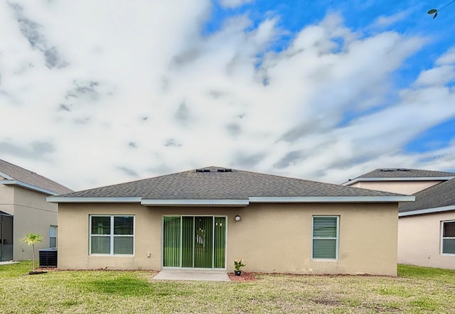 back of property featuring a shingled roof, a lawn, and stucco siding