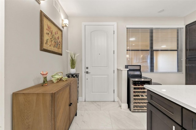 interior space with wine cooler, marble finish floor, and baseboards