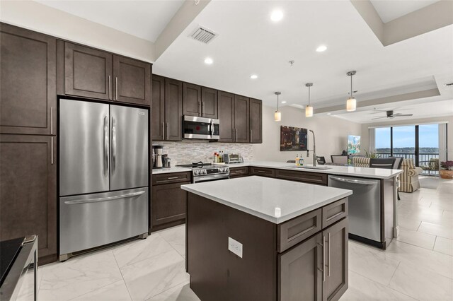 kitchen featuring stainless steel appliances, visible vents, decorative backsplash, a sink, and a peninsula