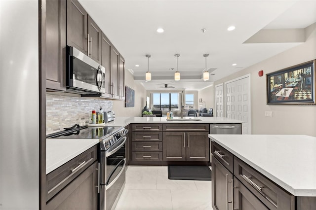 kitchen featuring recessed lighting, a peninsula, light countertops, appliances with stainless steel finishes, and decorative backsplash