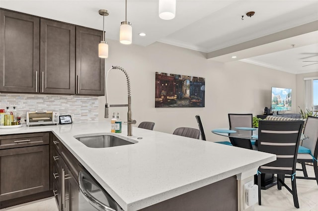 kitchen with a peninsula, dishwasher, dark brown cabinets, and a sink