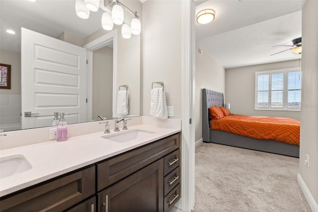 ensuite bathroom featuring ceiling fan, connected bathroom, a sink, baseboards, and double vanity