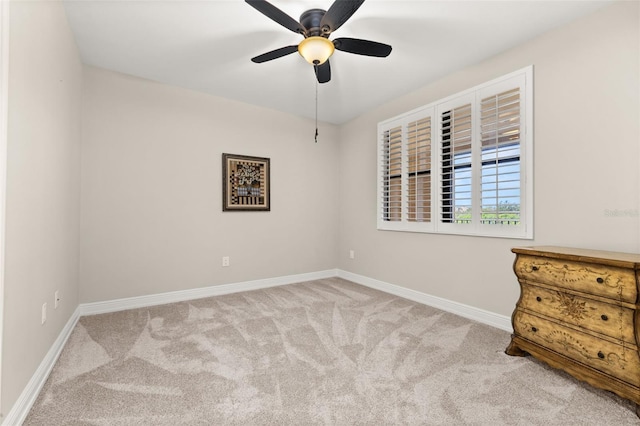 carpeted spare room featuring a ceiling fan and baseboards