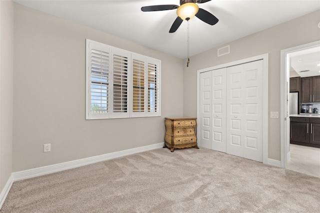 unfurnished bedroom with light carpet, visible vents, baseboards, ceiling fan, and a closet