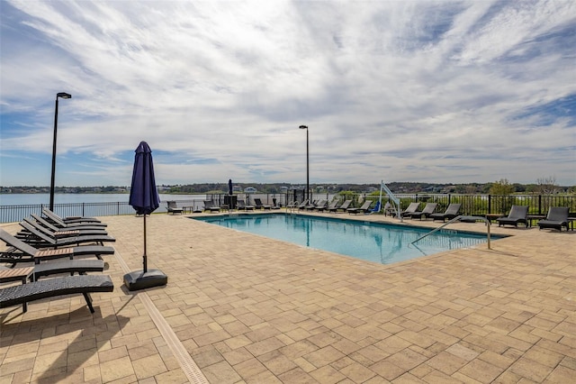 pool with a water view, fence, and a patio