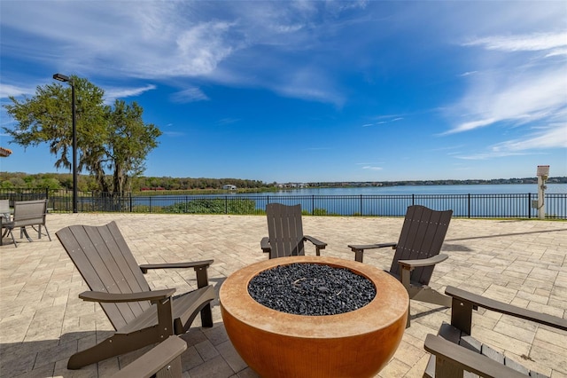 view of patio / terrace featuring a water view, fence, and a fire pit