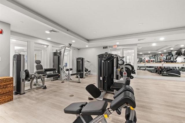 gym featuring recessed lighting, a raised ceiling, visible vents, and light wood-style floors